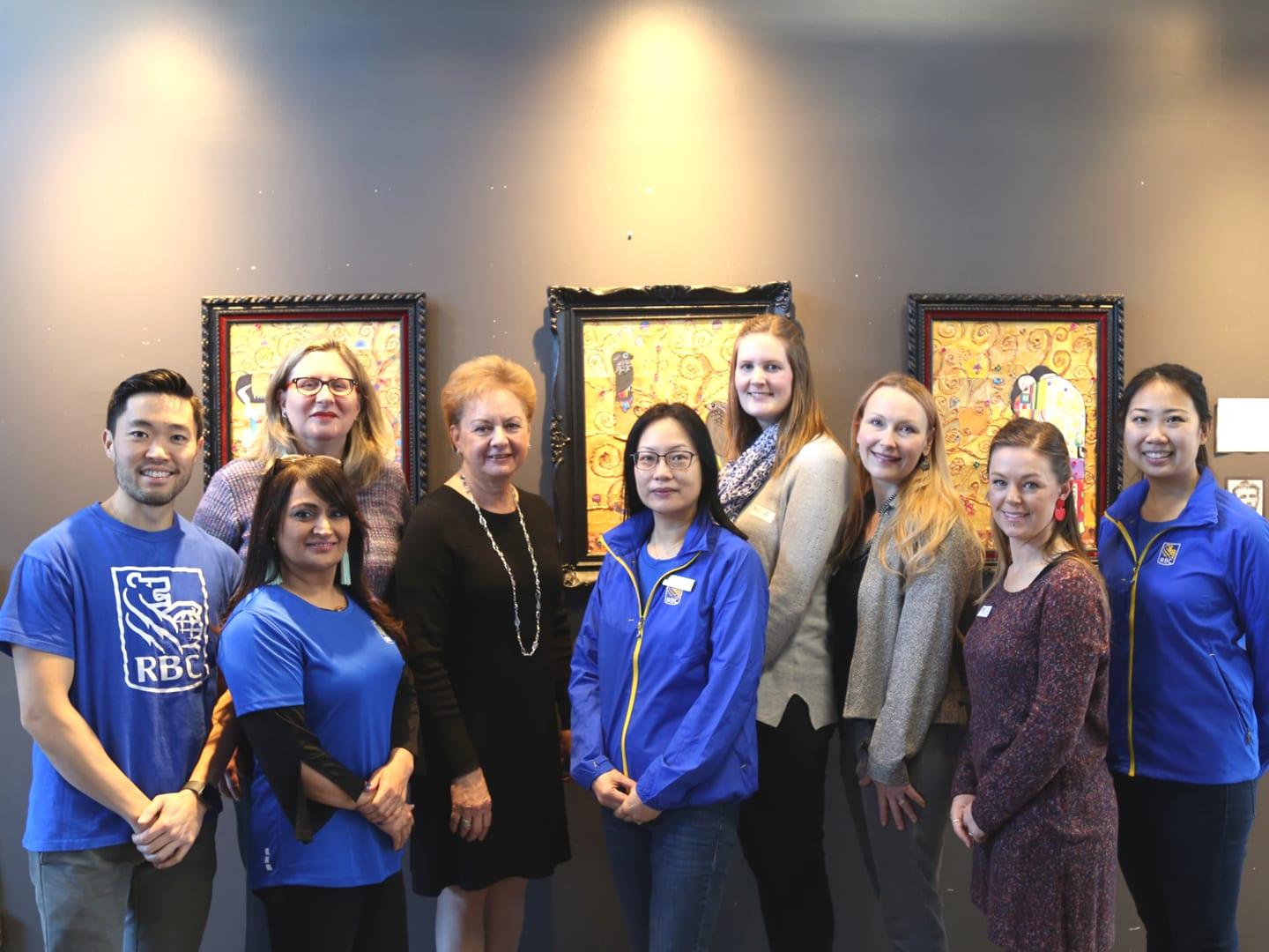 Community Arts Council board members, Reach to Teach teachers, and William Mah and his team of RBC volunteers pose in front of student artwork at the Collaboration Celebration Luncheon on January 17, 2020.